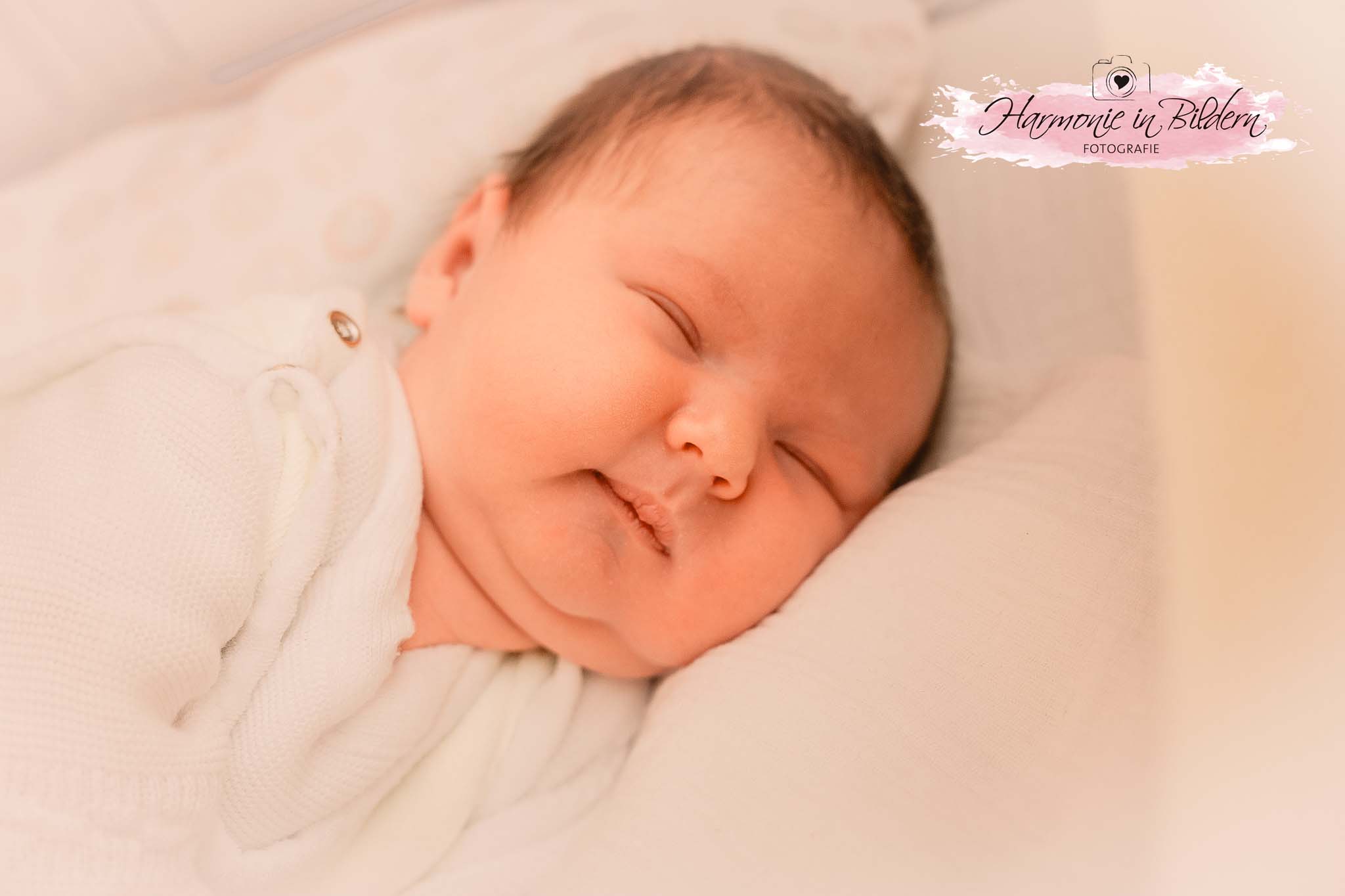 Ein Baby mit dünnem, dunklem Haar auf einem Kopfkissen. 