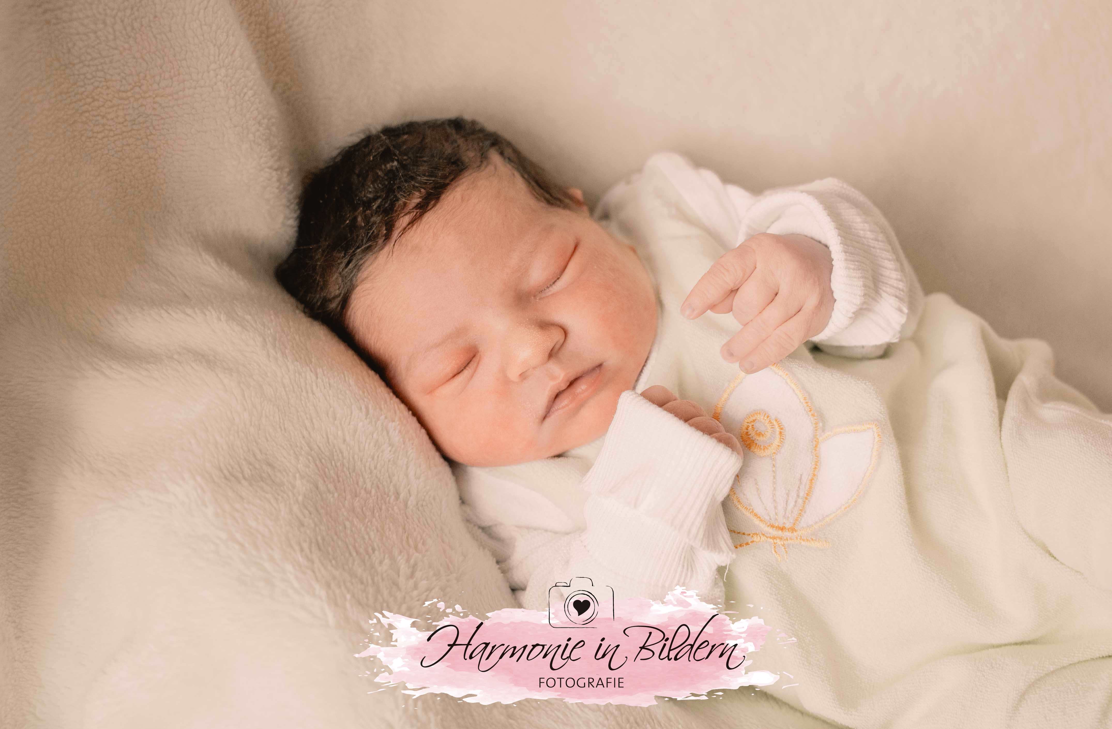 Baby mit dunklen Haaren auf heller Decke