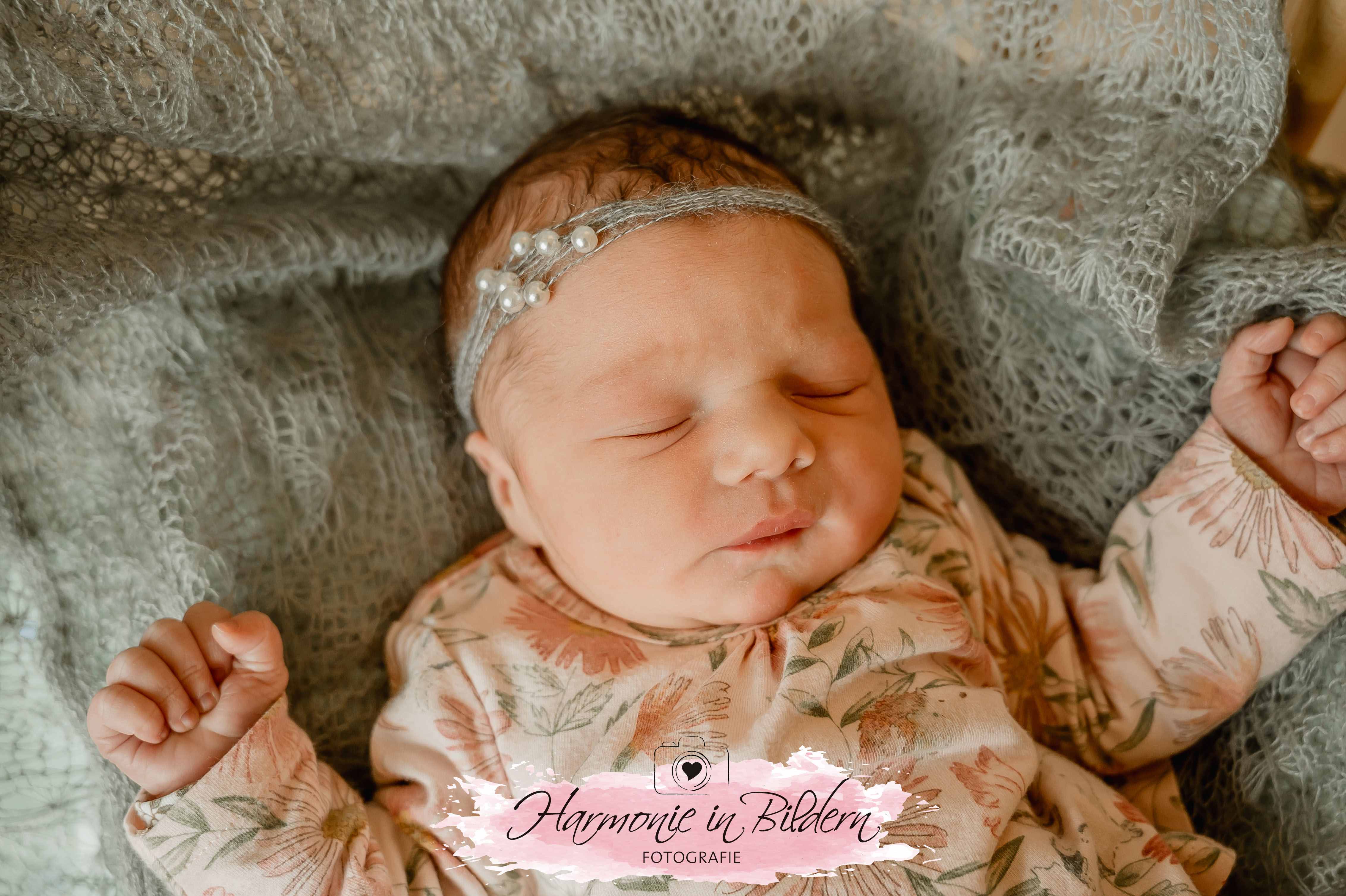 Neugeborenes auf grauer Decke mit Haarband