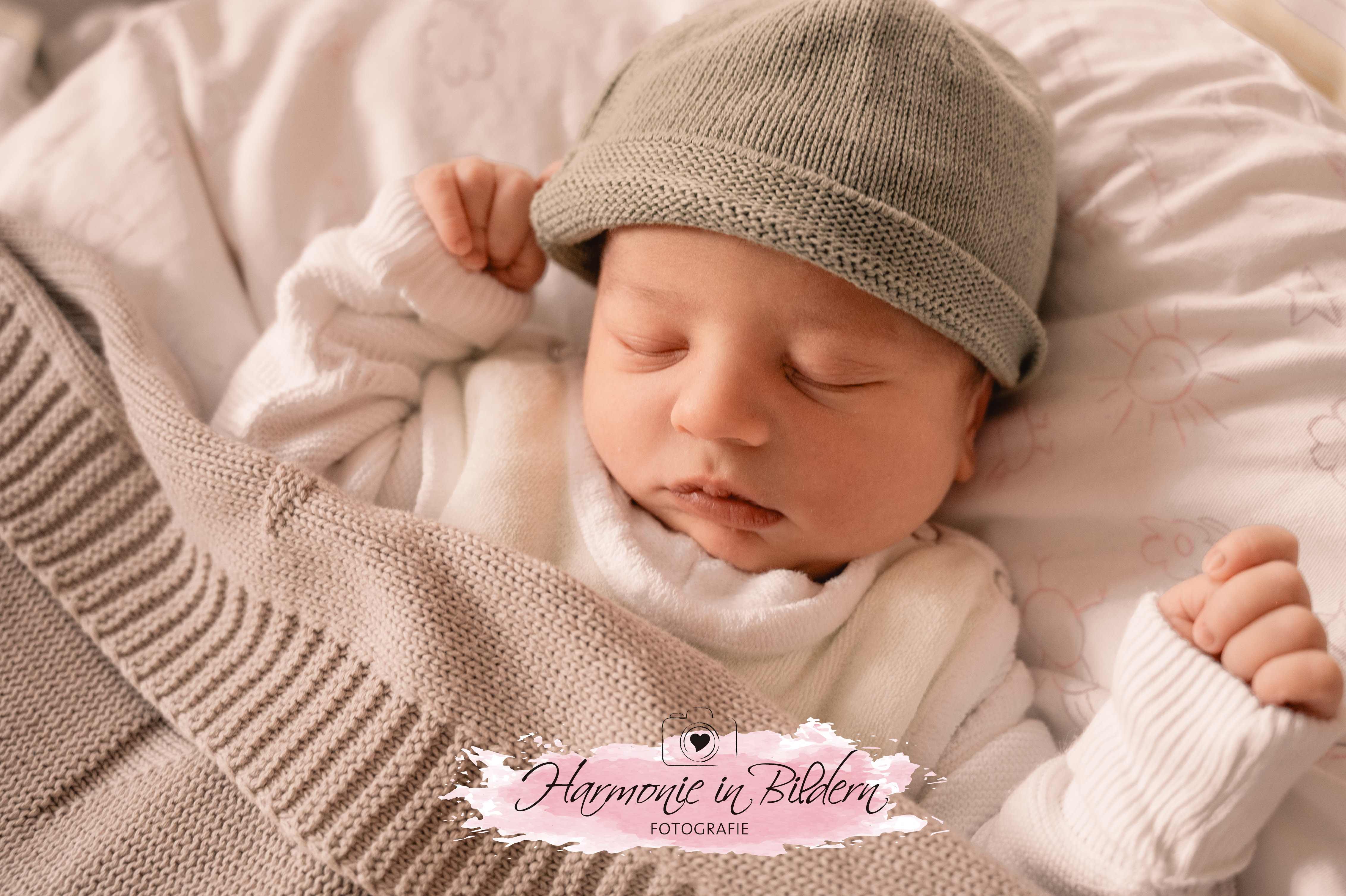 Neugeborener Junge schlafend  mit grüner Mütze