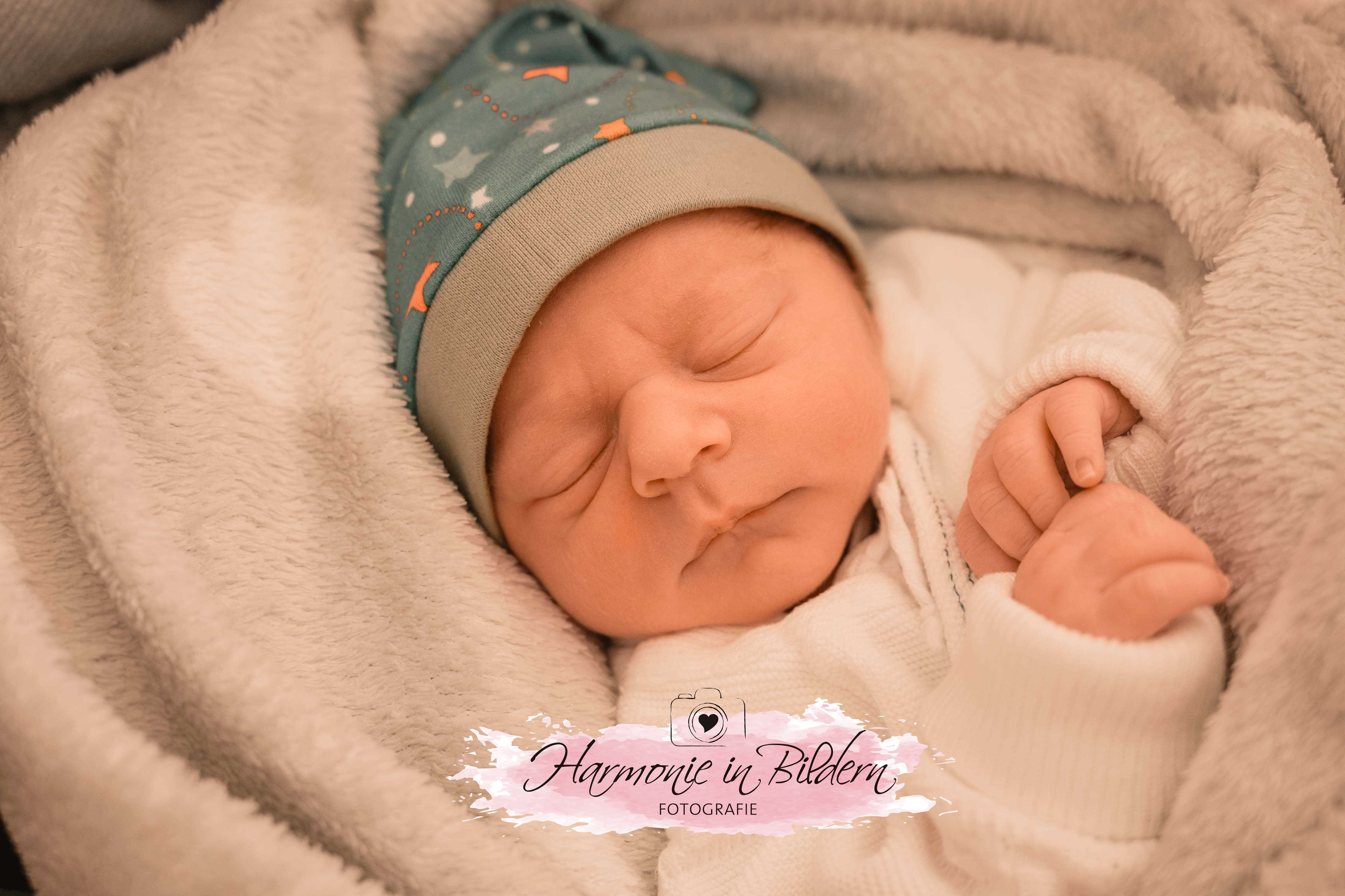 Neugeborener Junge in Decke und Mütze