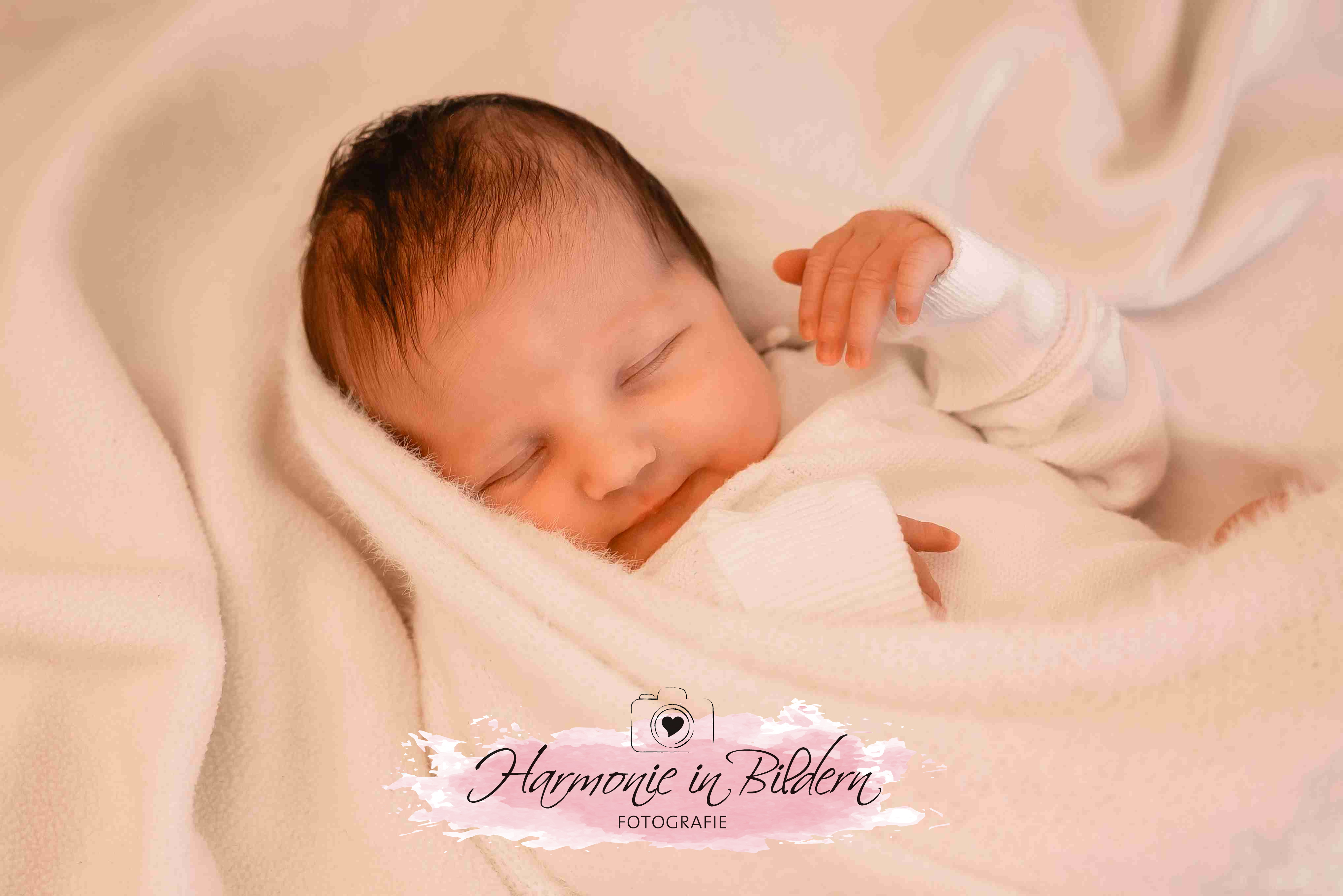 Neugeborenes Mädchen mit dunklen Haaren auf weißer Decke