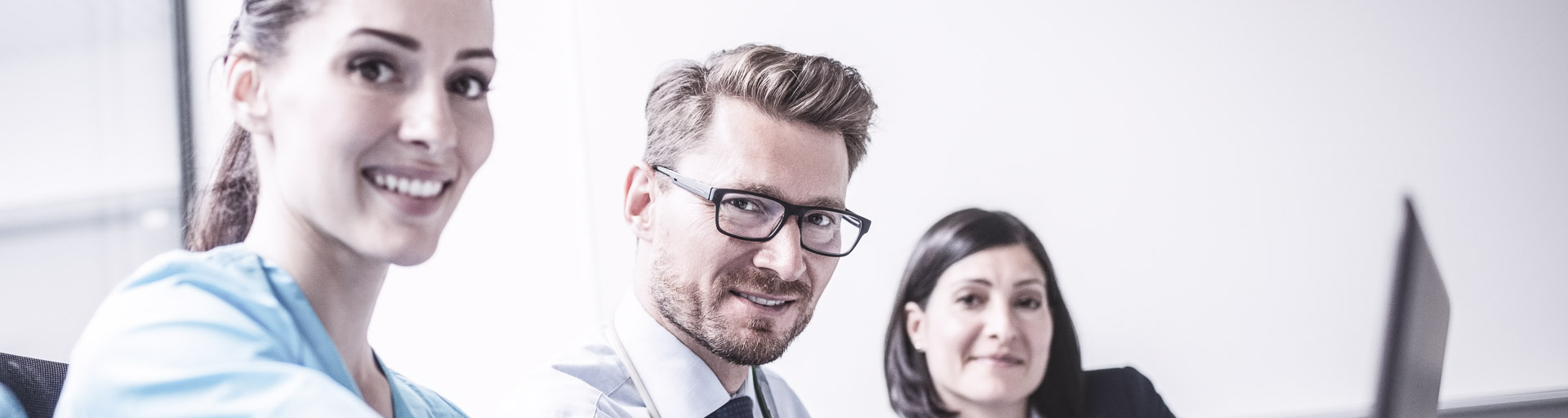 Drei Menschen schauen auf einen Laptop