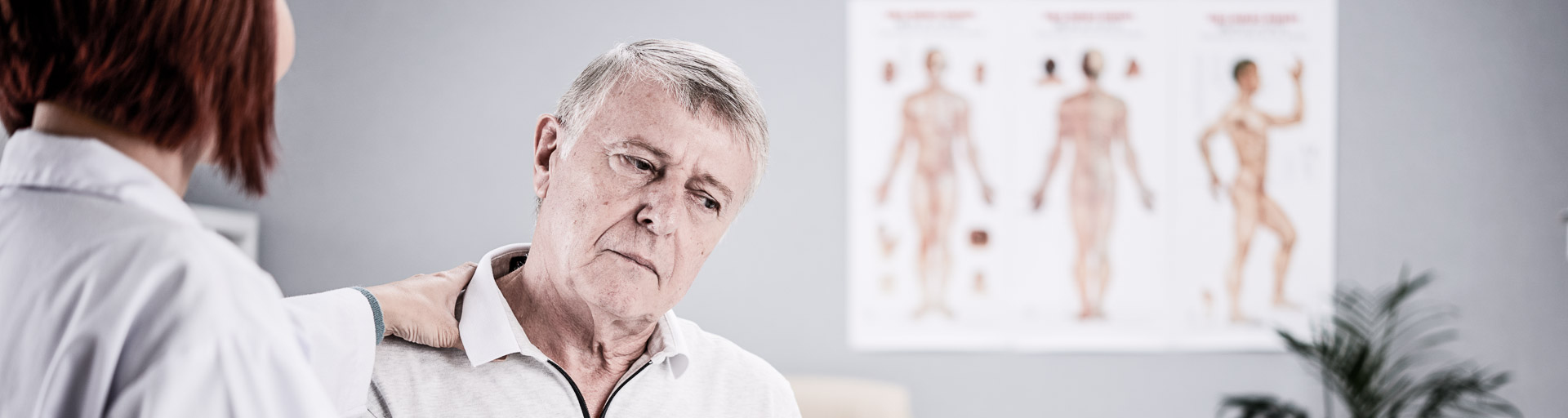 Ärztin legt die Hand auf die Schulter eines älteren Patienten
