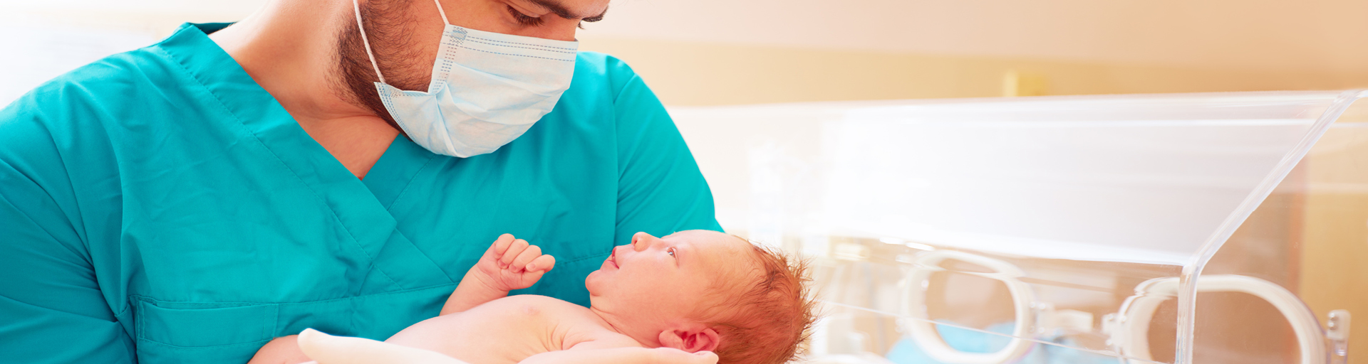 Ein Pfleger hält ein Neugeborenes im Arm.