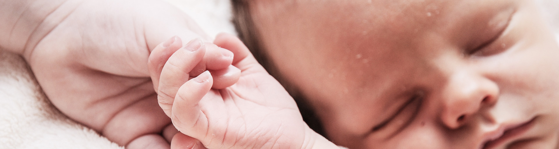 Neugeborenes hält Hand seiner Mutter