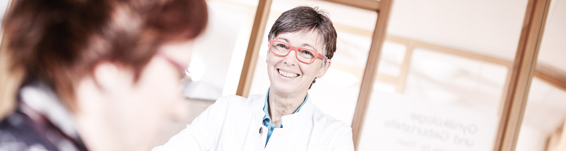 Ärztin spricht am Empfangstresen mit einer Krankenpflegerin