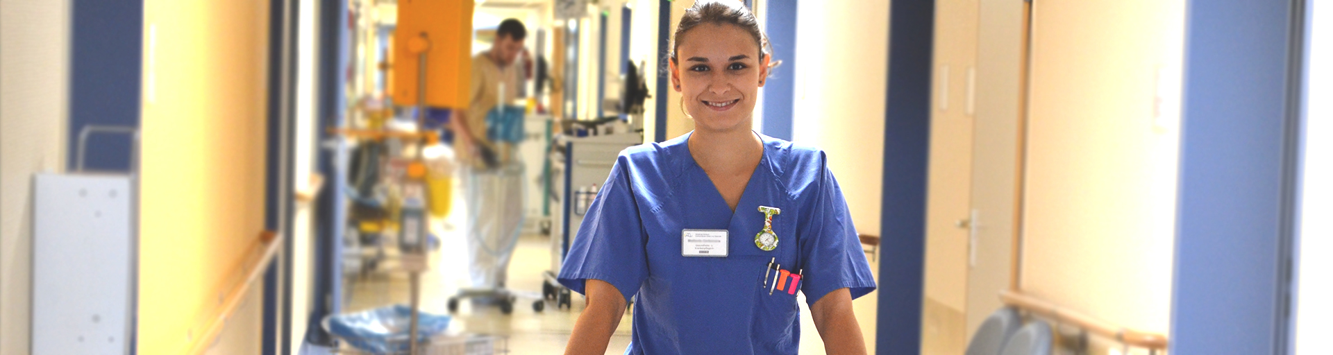 Pflegerin steht auf dem Krankenhausflur und lächelt in die Kamera