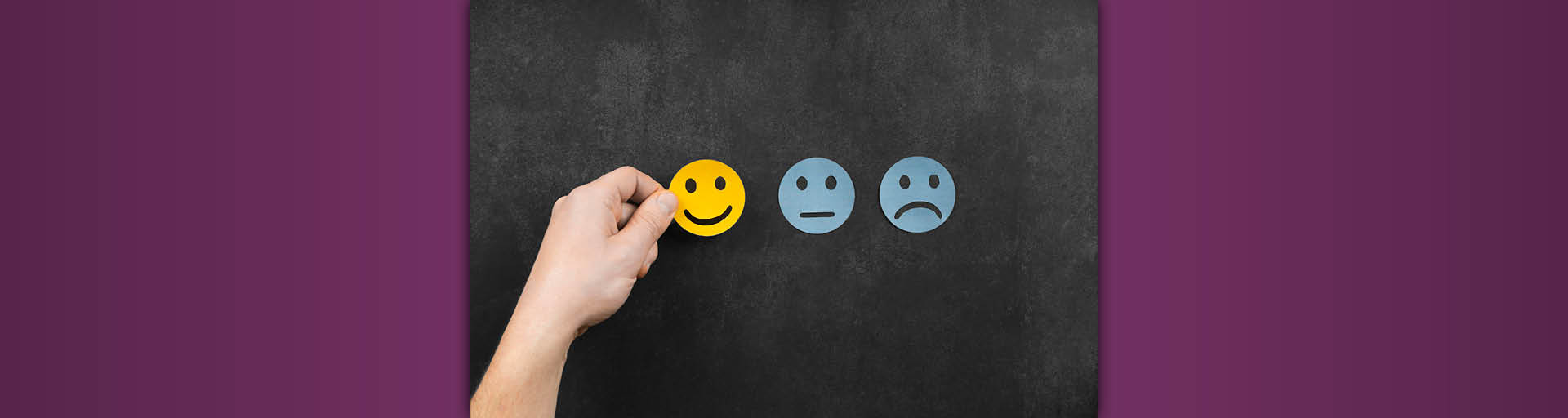 Eine Hand legt einen lächelnden Smiley auf einen Tisch.